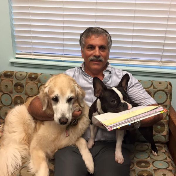 A vet relaxes on a couch, accompanied by two dogs